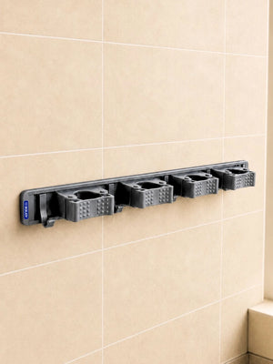 Grey BOXJOY wall-mounted broom and mop holder with four grips and five hooks installed on a tiled wall.