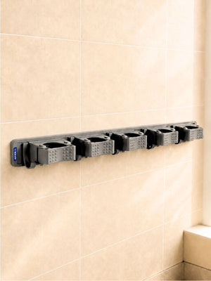 Grey BOXJOY wall-mounted broom and mop holder with five grips and six hooks installed on a tiled wall.