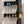 Black BOXJOY modular shoe wardrobe with 6 shelfs, smoky transparent doors, and side hooks, neatly storing various pairs of shoes.
