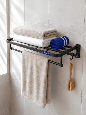Black BOXJOY bathroom shelfs holding folded towels and a hanging wooden body brush.