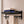 Black BOXJOY bathroom shelfs holding folded towels and a hanging wooden loofah brush.
