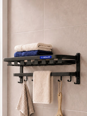 Black BOXJOY bathroom shelfs holding folded towels and a hanging wooden loofah brush.