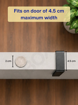 Top-down view showing the grey bracket easily fitting on a door with a 4.5 cm maximum width next to a coin.